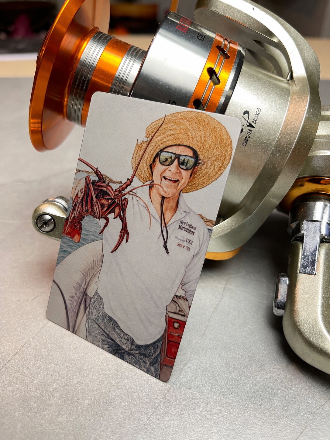 The Fisherman — metal card leaning against a fishing reel
