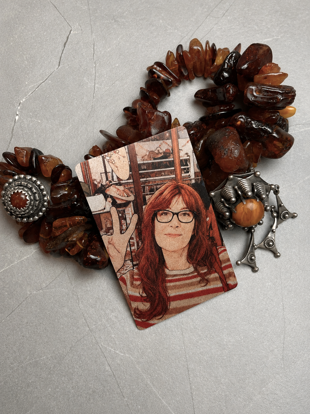 The Collector — illustrated metal card among amber jewellery